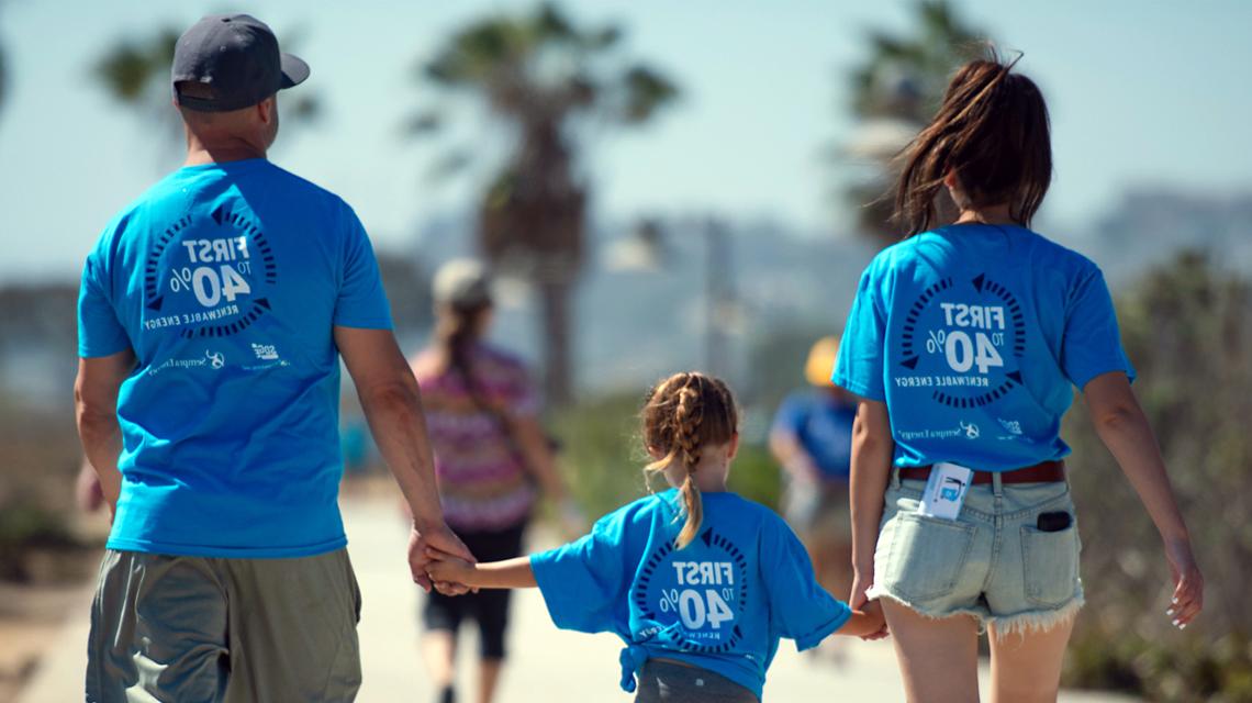 A family wearing celebratory shirts holding hands and walking